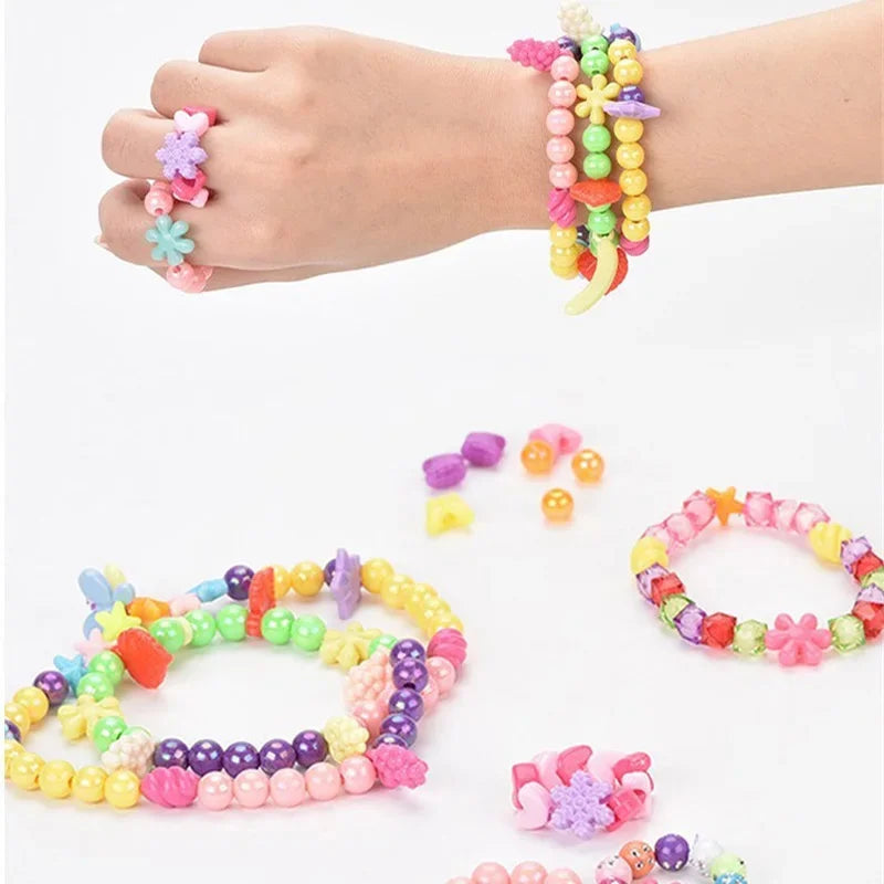 A hand wearing a colorful beaded bracelet and loose beads, with several finished bracelets displayed.
