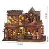 A detailed miniature dollhouse kit of a seaside beach house featuring various shops and an LED light.