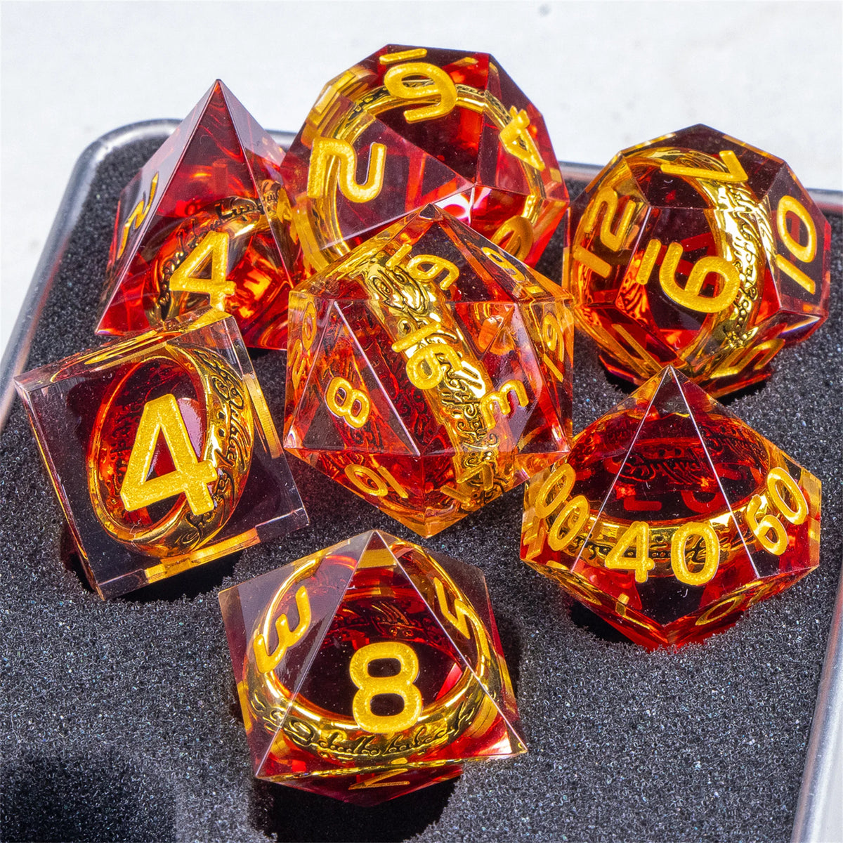 A set of resin dice featuring golden elven numbers on transparent red and amber dice.