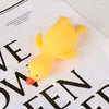 A bright yellow, soft duck squeeze toy is shown resting on a piece of paper with black text.