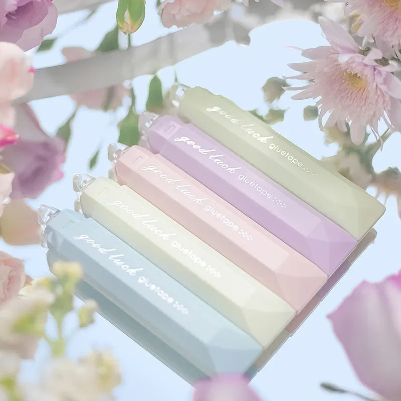 A close-up shot of a 4-pack of pastel colored adhesive dot tape glue rollers with pink, purple, and green shades against a so