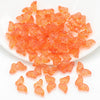 A pile of small, translucent orange glass butterfly beads for jewelry making.