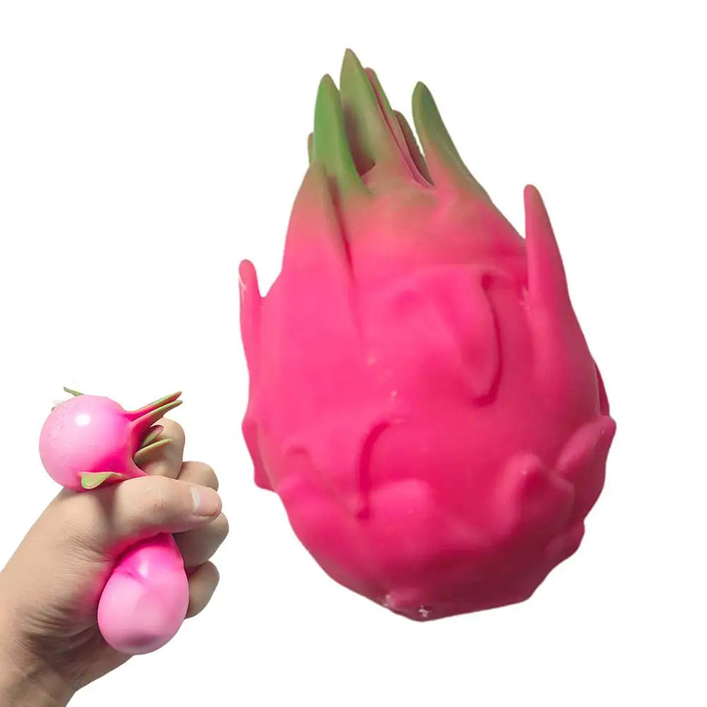 A hand holds a bright pink dragon fruit squishy stress relief toy with green tips.