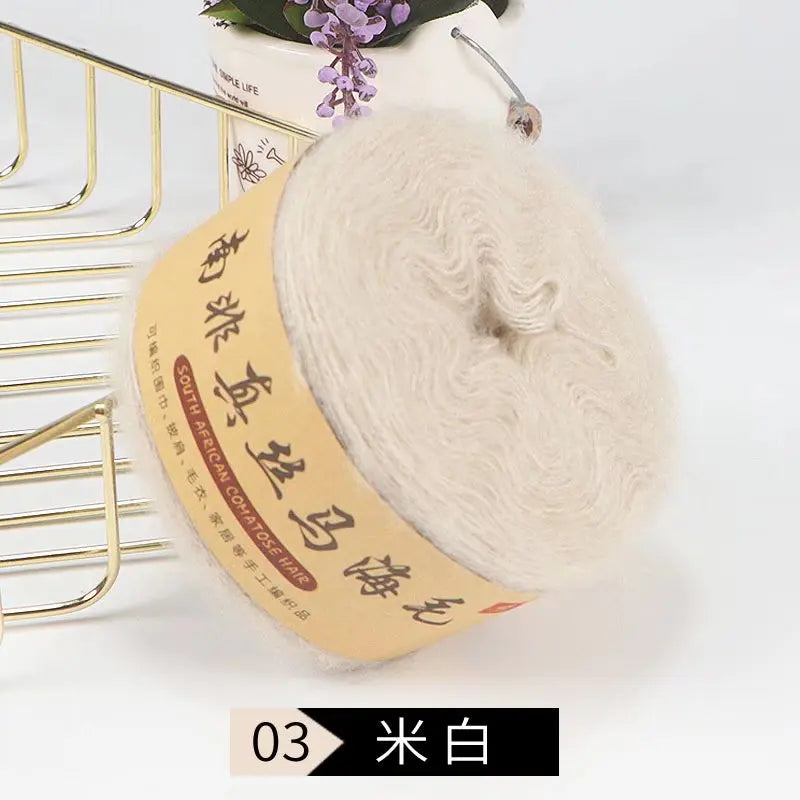 A ball of light beige silk mohair blended yarn for knitting, displayed next to a gold wire rack.