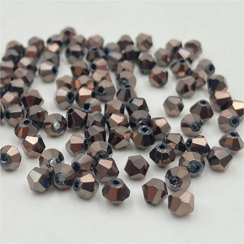 A pile of small, faceted bicone crystal glass beads in a bronze or rose gold color.