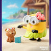 A yellow Minion figure wearing oversized glasses and a green skirt stands next to a small brown plush toy on a sandy surface.