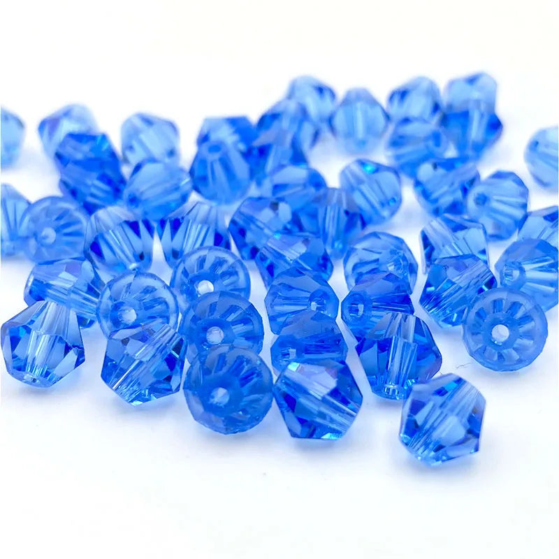 A pile of small, faceted blue crystal glass beads for jewelry making.