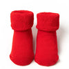 Pair of red knitted baby anti-slip cotton socks with festive Christmas designs