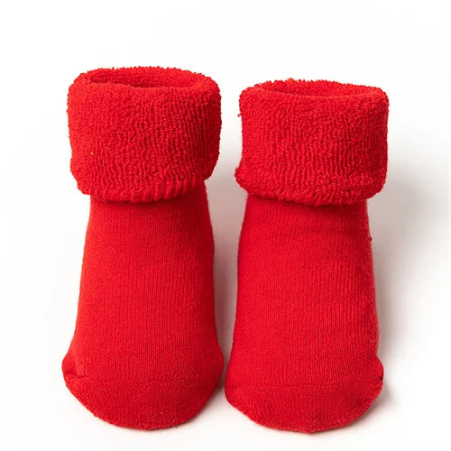 Pair of red knitted baby anti-slip cotton socks with festive Christmas designs