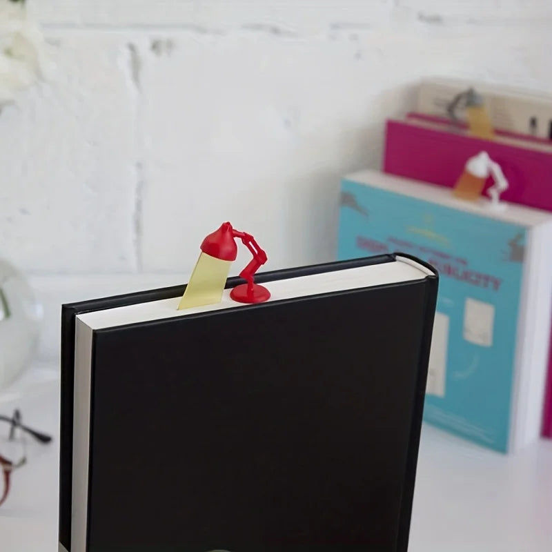 A black book with a yellow bookmark featuring a red cartoon desk lamp.