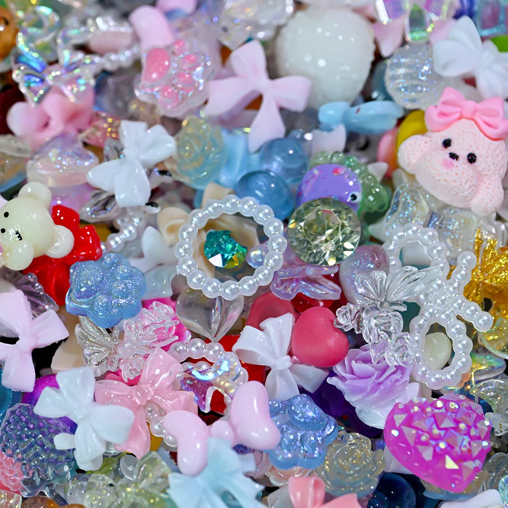 A close-up of a mix of multicolor resin nail charms featuring various shapes and glitter effects.