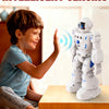 A young boy interacts with an intelligent sensing robot toy on a wooden table.