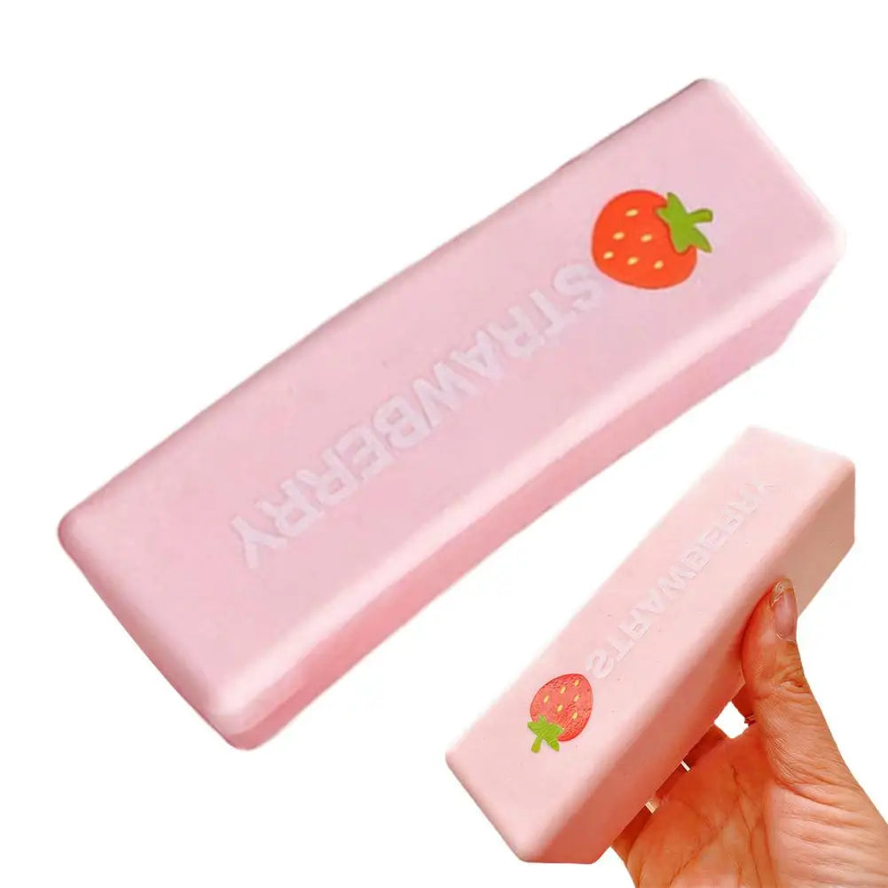 A pink strawberry milk squishy stress relief toy is shown being held by a hand.
