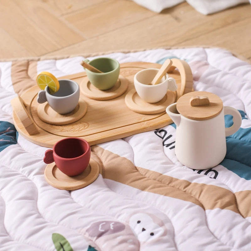 A wooden pretend play tea party set with cups and saucers arranged on a quilted white blanket.