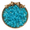 A round dish filled with bright blue glass crackle beads tied with a gold ribbon.