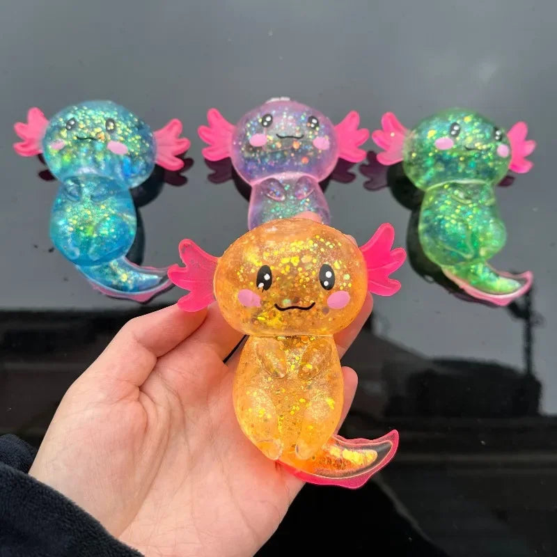 A hand holds a bright orange squishy axolotl stress relief toy with pink and green accents.