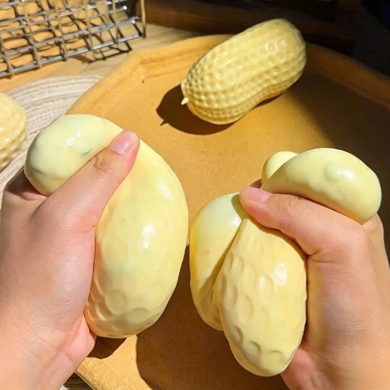 Hands holding and squeezing a yellow peanut butter squishy stress ball on a wooden surface.