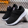 A pair of black breathable mesh kids' sneakers with hook-and-loop closures shown on a white surface.