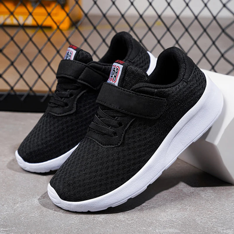 A pair of black breathable mesh kids' sneakers with hook-and-loop closures shown on a white surface.