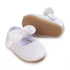 White lace-trimmed baby girl moccasin shoes with a bow and tan sole