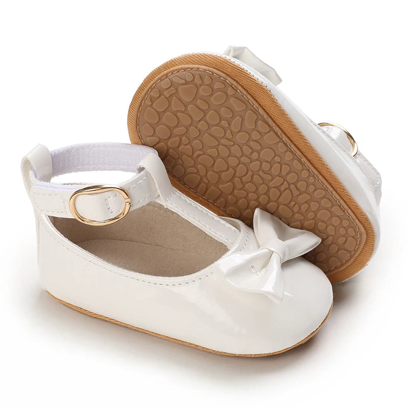 White lace-trimmed baby girl moccasin shoes with a bow and tan sole