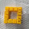 A yellow infinity cube fidget toy with interlocking plastic pieces resting on a white textured surface.