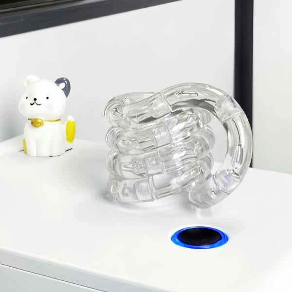 A clear crystal fidget twist rope is displayed next to a white cat figurine on a white surface.