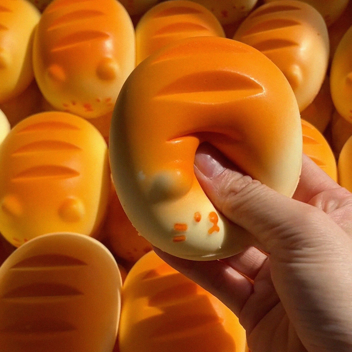 A hand holds an orange giant chick squishy toy, showing its texture and size.