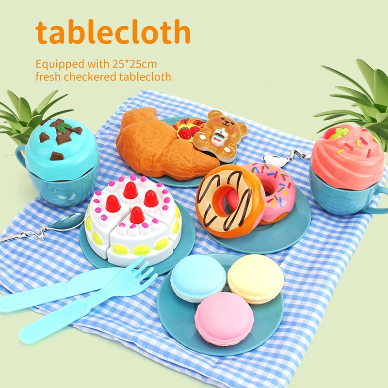 A tablecloth is set with a pretend play picnic and tea party arrangement featuring food items like bread, donuts, and macaron