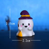 A white cartoon pumpkin bear figurine wearing a purple hat and holding a yellow pumpkin.