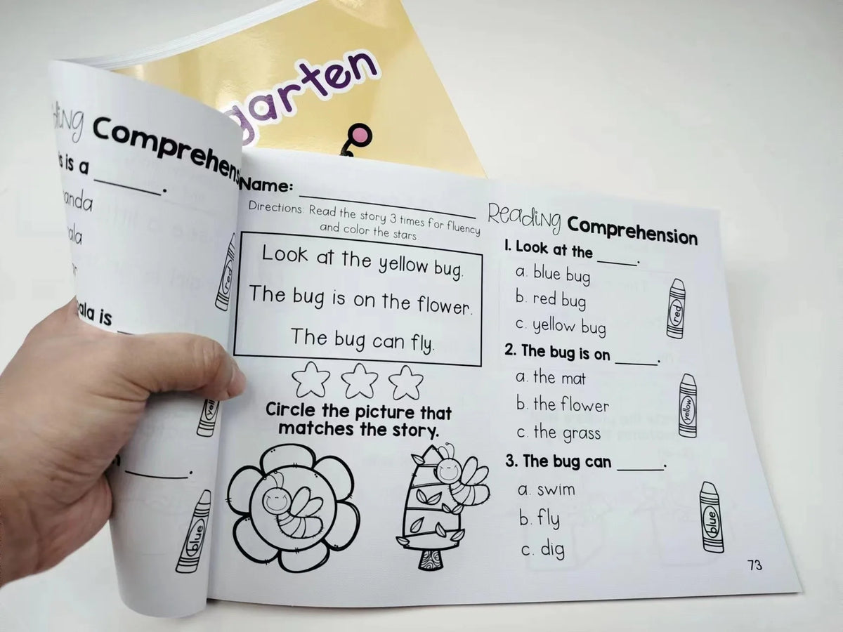A hand holds an open children's reading comprehension book with illustrations and text.