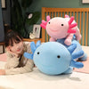 A person is leaning on a large blue axolotl plush pillow, with a pink axolotl plush resting beside it.