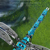 A close-up of a blue and silver mechanical dragonfly model kit with translucent blue lights, set against a blurred green back