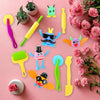 A collection of colorful creative play dough tools including spatulas, rollers, and sculpting implements arranged on a pink b
