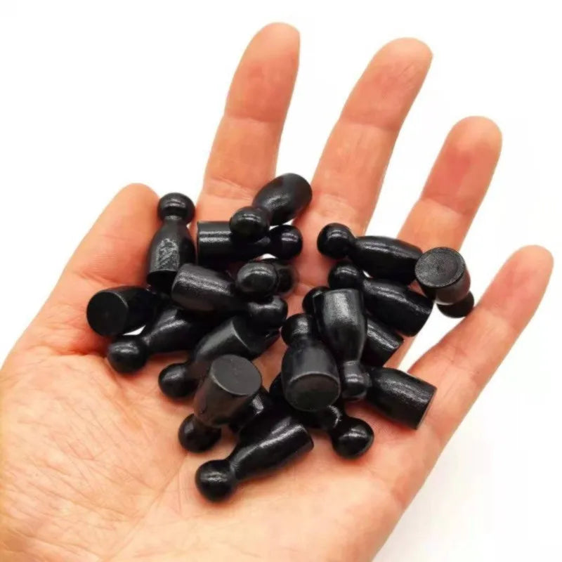 A hand holds a set of ten black wooden chess pawns for board games.