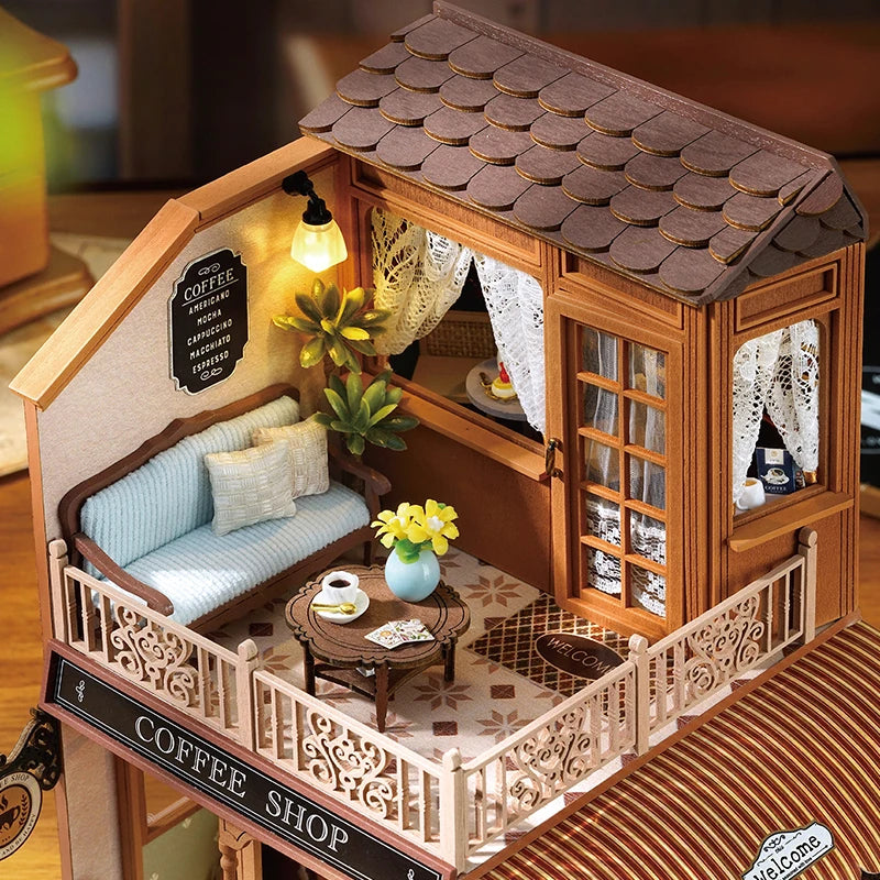 A wooden miniature dollhouse kit featuring a coffee shop facade with detailed furniture and lighting.