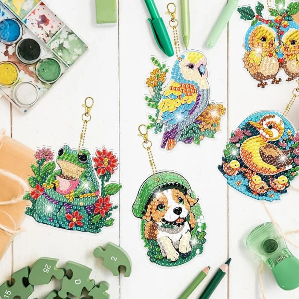 A collection of animal owl diamond painting keychains and craft materials laid out on a white surface.