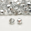A close-up of faceted, clear and silver crystal beads scattered on a white surface.