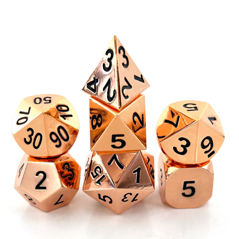 A set of three premium metal polyhedral dice with a gold finish arranged in a pyramid shape.