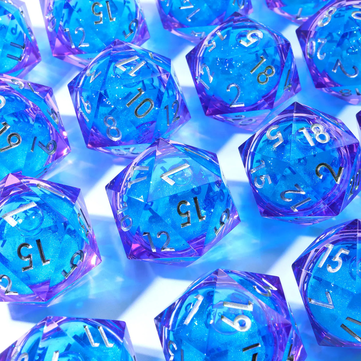A collection of handmade resin D20 dice featuring a blue and purple liquid swirl effect.