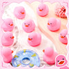 A set of pink mini rubber ducks resting on a wooden surface with soft fabric background.
