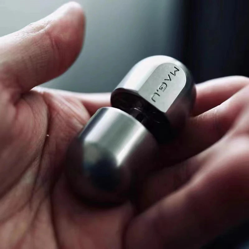 A hand holds a stainless steel magnetic levitating fidget slider toy with the brand name MAGL engraved on it.