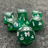 A collection of seven iridescent green acrylic polyhedral dice scattered on a dark gray surface.
