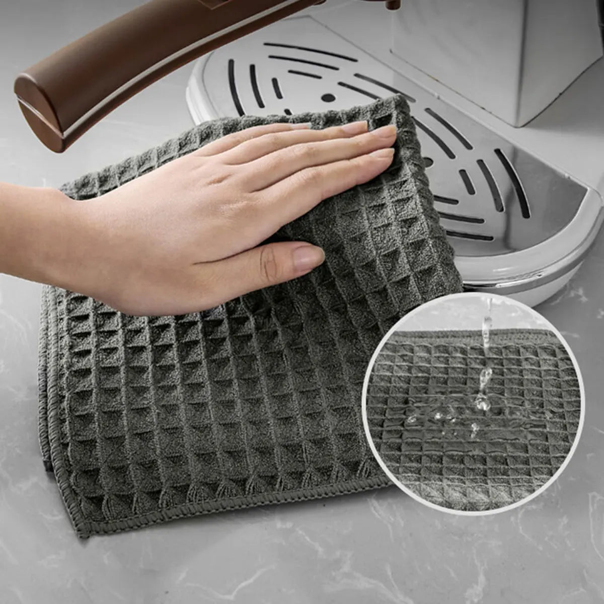 A hand is holding a gray, textured microfiber cleaning cloth over a white appliance.