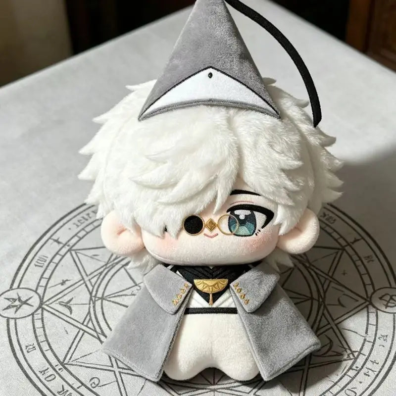 A soft collectible plush doll of a character wearing a gray witch hat and a gray coat, sitting on a diagram.