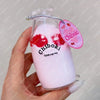 A hand holds a pink glass bottle filled with liquid and red squishy toys labeled Chiboki Drink cup toy