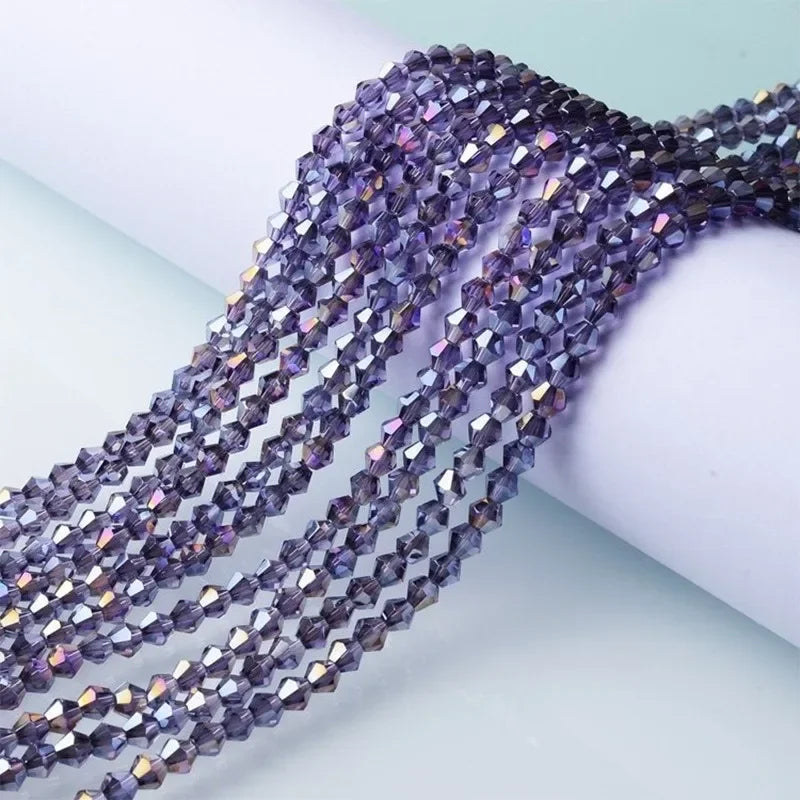 A close-up of purple and blue faceted glass crystal beads strung together for jewelry making.