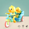 A yellow duck plush toy is seated in a blue electric tricycle with visible light and music features.