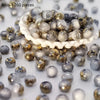 A pile of round, iridescent beads in shades of gray and gold for jewelry making