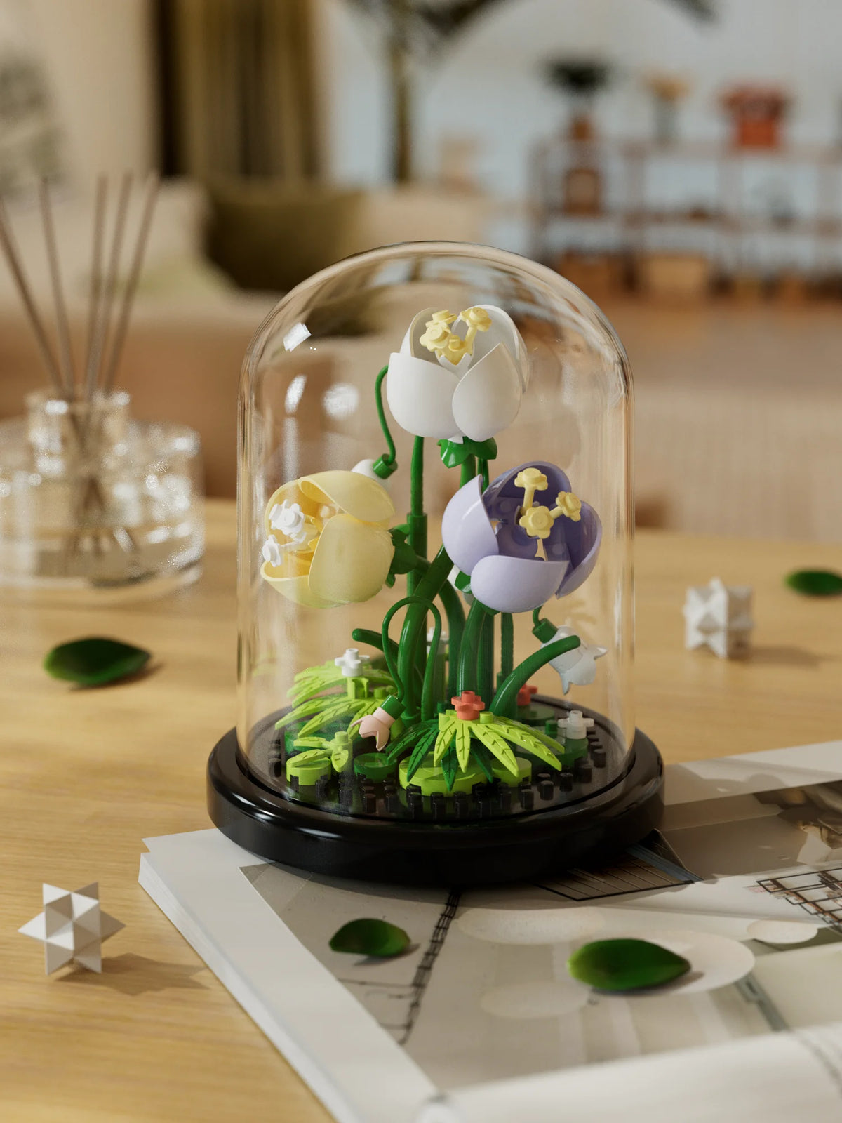 A glass dome display featuring a miniature green plant with white and purple flowers.
